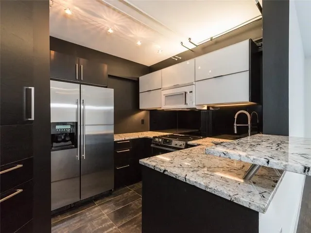 a kitchen with granite countertop a refrigerator and a stove top oven
