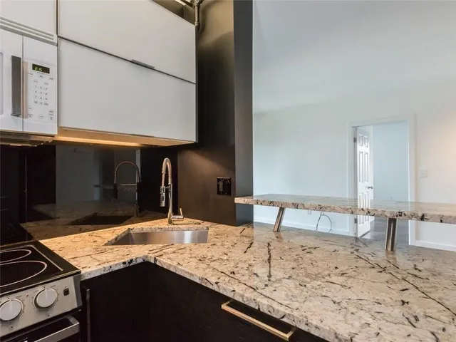 a kitchen with kitchen island granite countertop a sink and cabinets