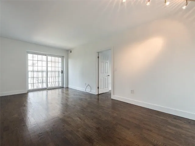 a view of an empty room with wooden floor and window