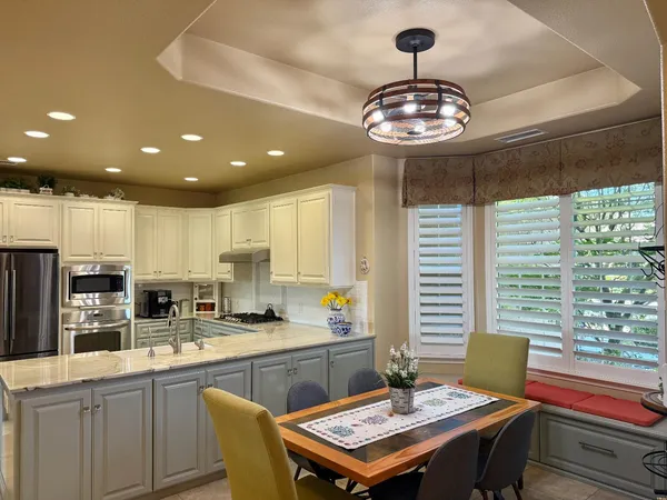 a kitchen with stainless steel appliances a sink a stove a refrigerator dining table and chairs