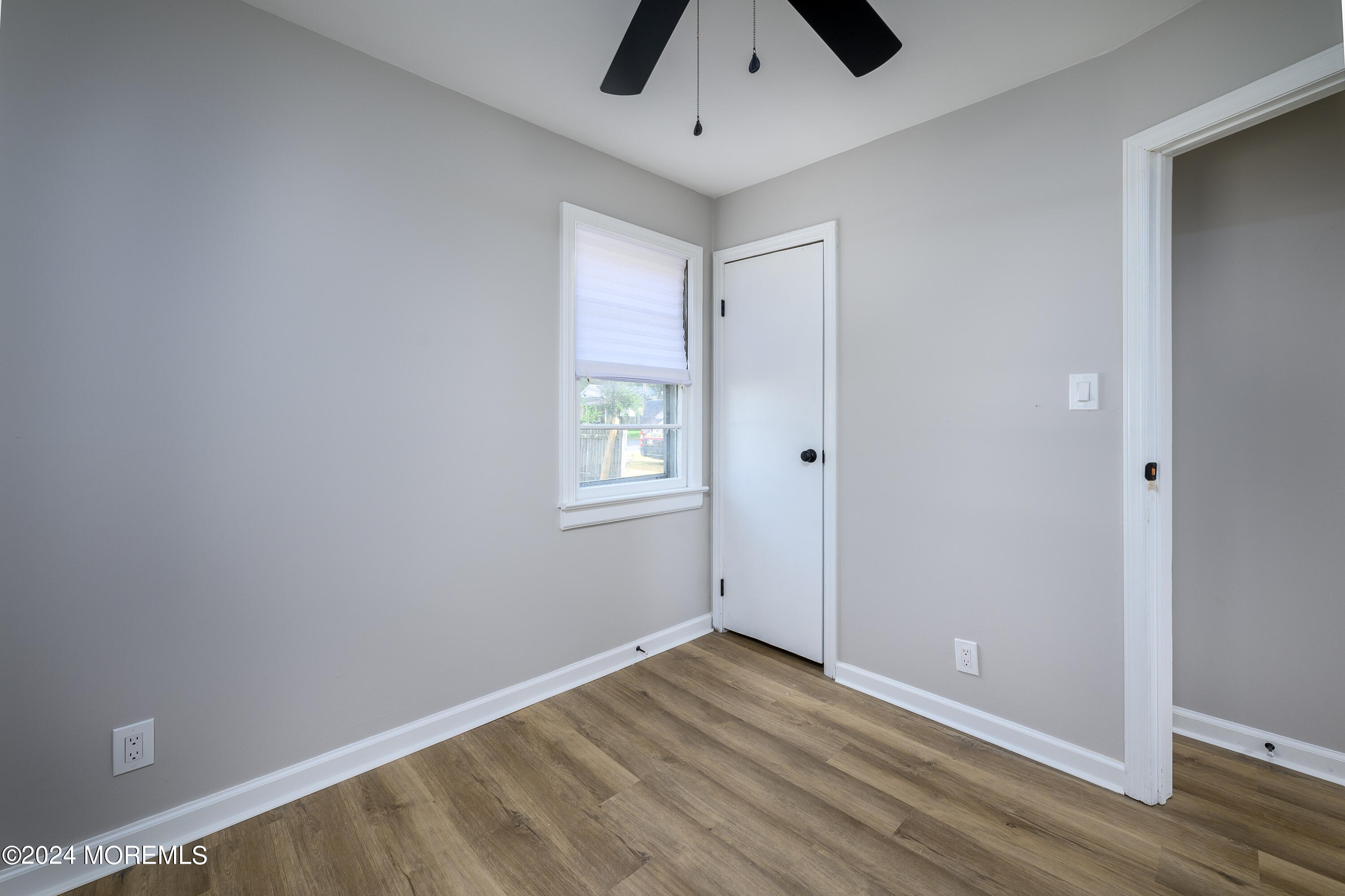 554 Lillie Road Toms River, NJ 08753 - Photo 12 of 26 an empty room with wooden floor cabinet and windows
