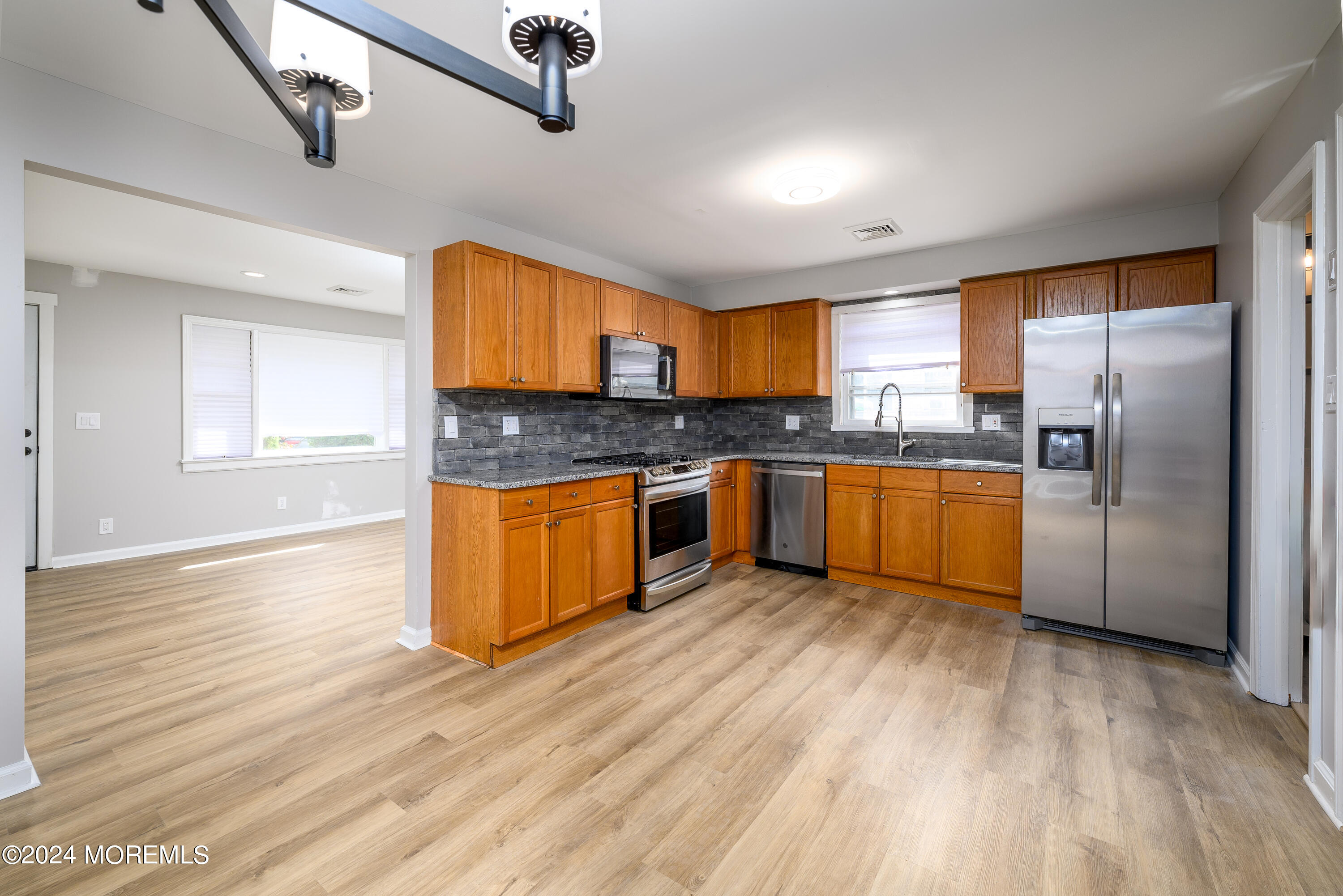554 Lillie Road Toms River, NJ 08753 - Photo 14 of 26 a kitchen with stainless steel appliances granite countertop a stove top oven a refrigerator and a sink with wooden floor