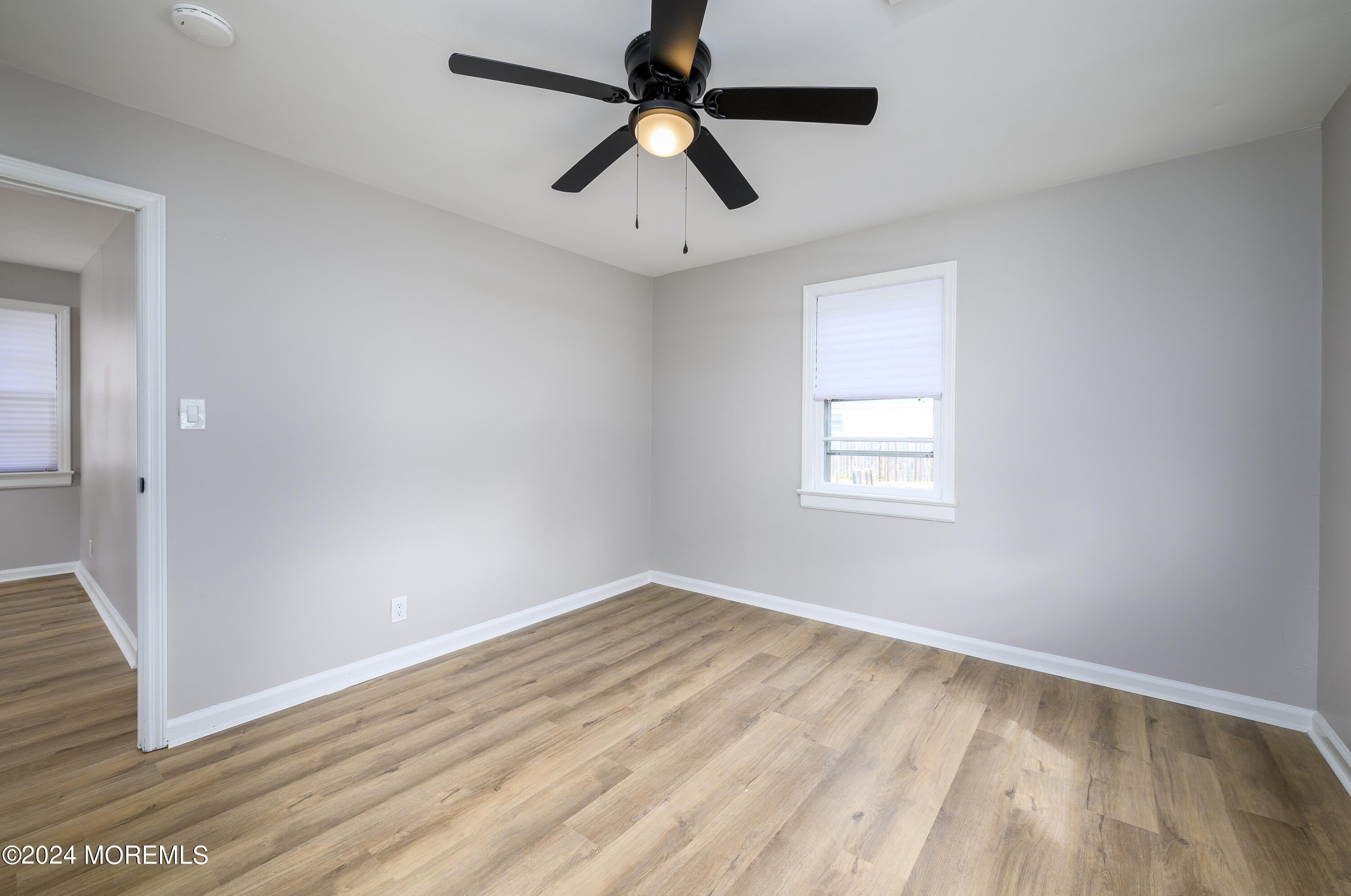554 Lillie Road Toms River, NJ 08753 - Photo 8 of 26 an empty room with wooden floor ceiling fan and windows