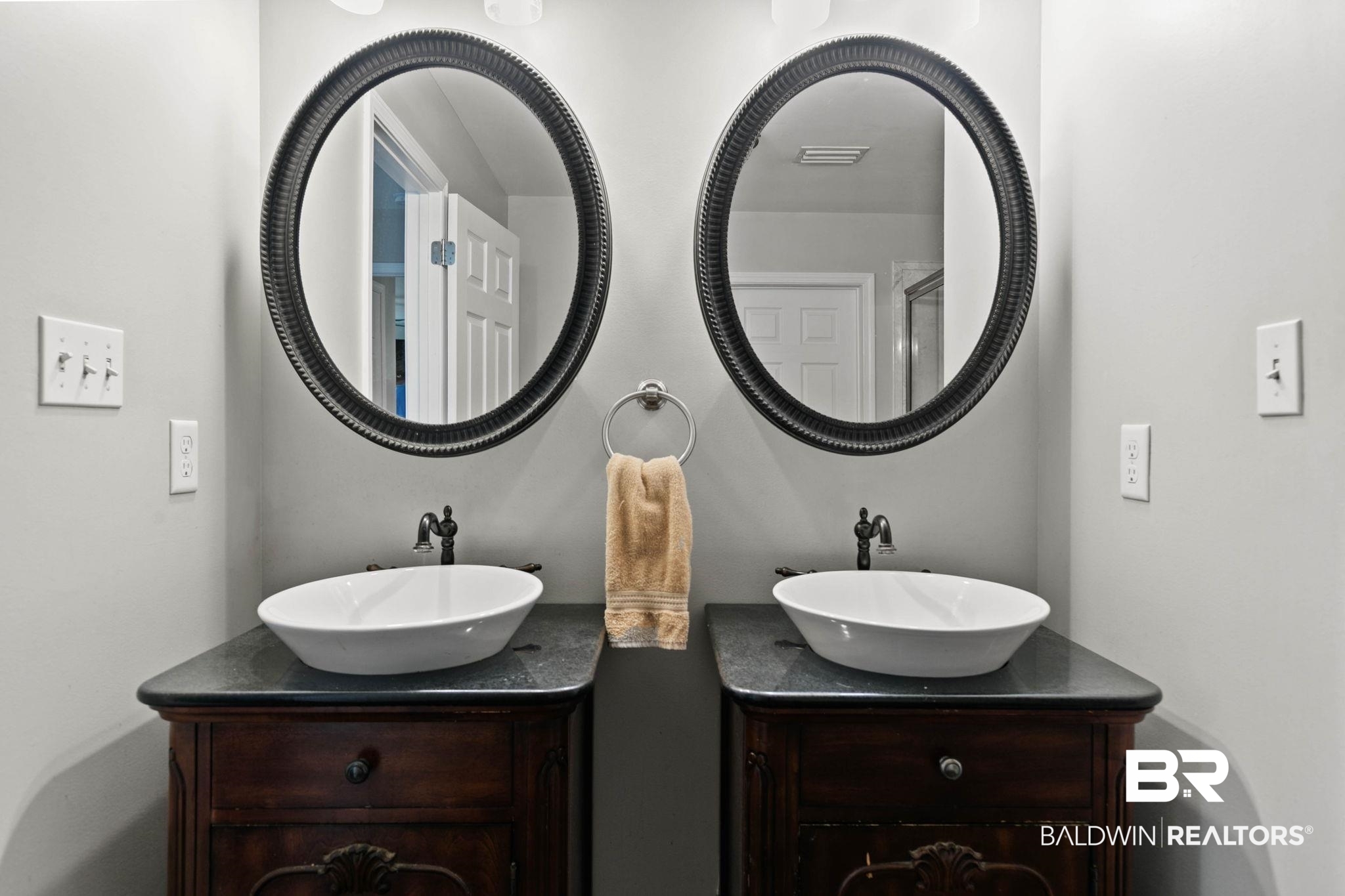 22810 High Ridge Road Fairhope, AL 36532 - Photo 37 of 78 Dual vanity with vessel sinks, dark wood cabinetry, black countertops, and oval framed mirrors