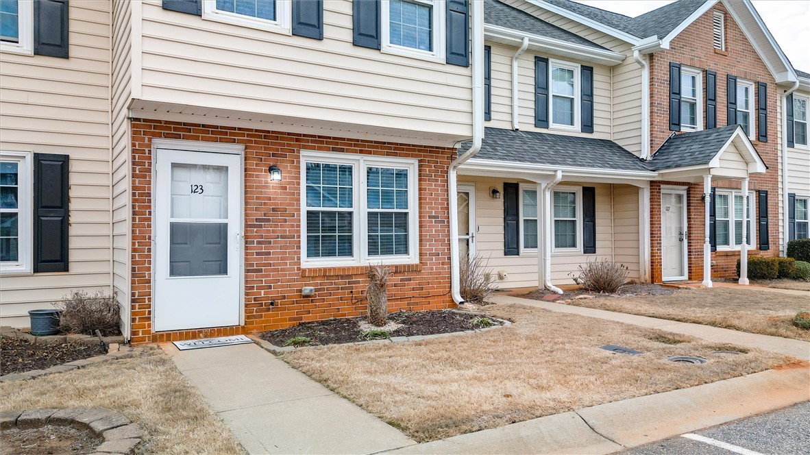 123 Trailside Lane Greenville, SC 29607 - Photo 3 of 29 This charming townhome features classic brick and siding, offering a cozy and inviting atmosphere.