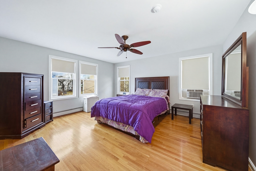 39 Hawthorne Street, Unit 39 Boston, MA 02119 - Photo 17 of 33 a spacious bedroom with a bed and dresser with wooden floor