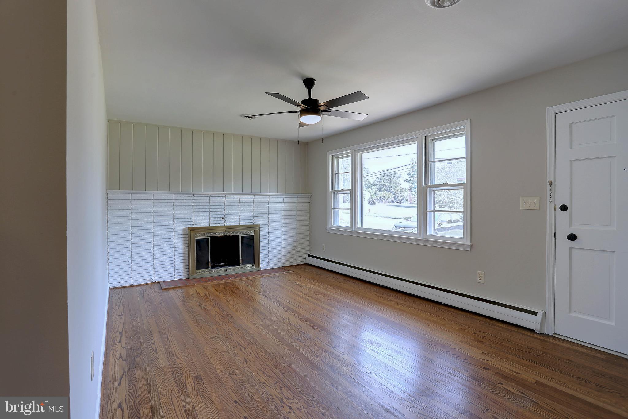 10355 Scaggsville Road Laurel, MD 20723 - Photo 9 of 41 an empty room with wooden floor fireplace and windows
