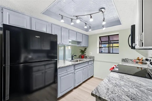 a kitchen with stainless steel appliances kitchen island granite countertop a refrigerator stove top oven and sink