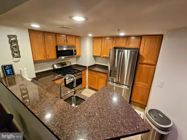 a room with wooden floor pool table and stainless steel appliances
