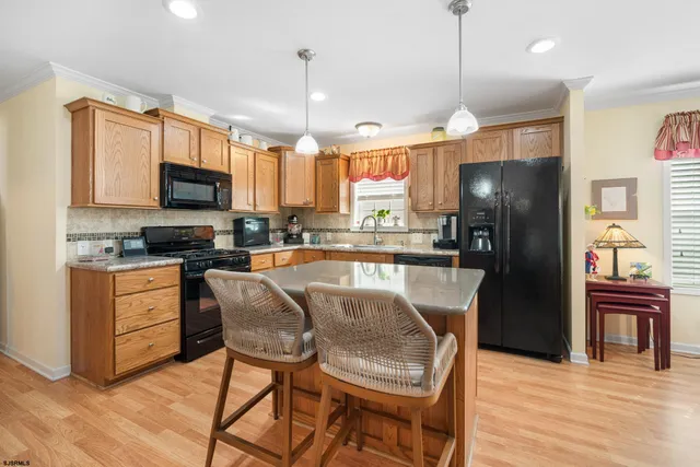 a kitchen with stainless steel appliances granite countertop a refrigerator a stove a sink dishwasher a dining table and chairs with wooden floor