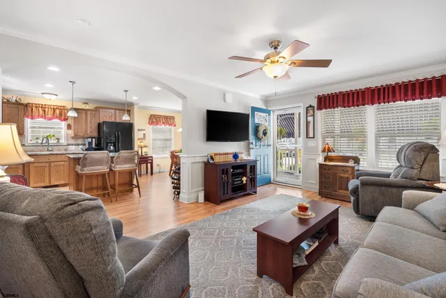 a living room with furniture a flat screen tv and kitchen view