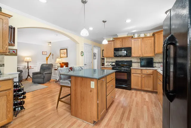 a kitchen with stainless steel appliances granite countertop a refrigerator a stove top oven a sink dishwasher and white cabinets with wooden floor