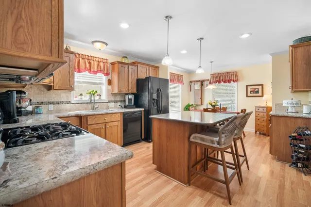 a kitchen with stainless steel appliances granite countertop a stove a sink dishwasher a refrigerator and white cabinets with wooden floor