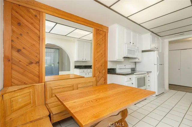 a large white kitchen with kitchen island a sink stainless steel appliances wooden floor and cabinets
