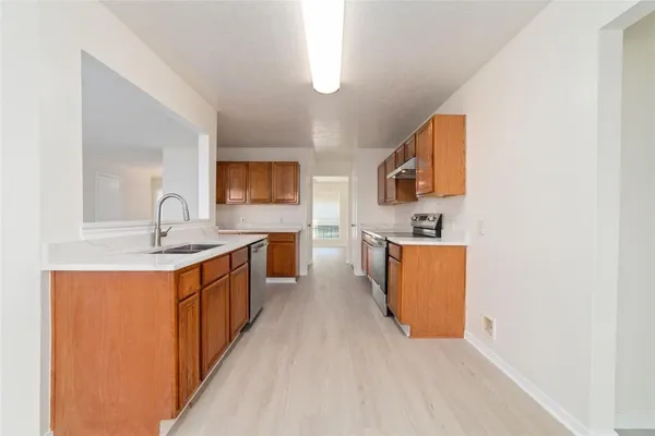 a large kitchen with stainless steel appliances granite countertop a sink and a stove with wooden floor