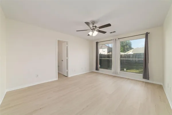 a view of an empty room with a window and a kitchen
