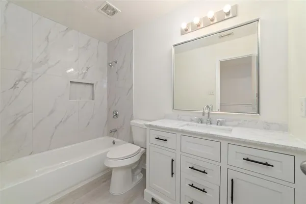 a bathroom with a granite countertop toilet a sink and bathtub