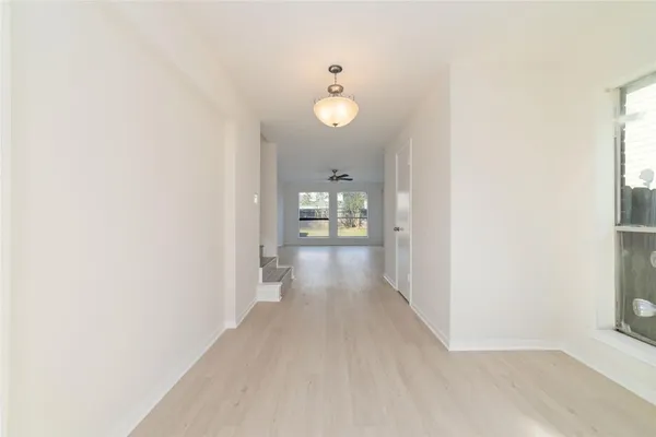 a view of a hallway with wooden floor and a bathroom