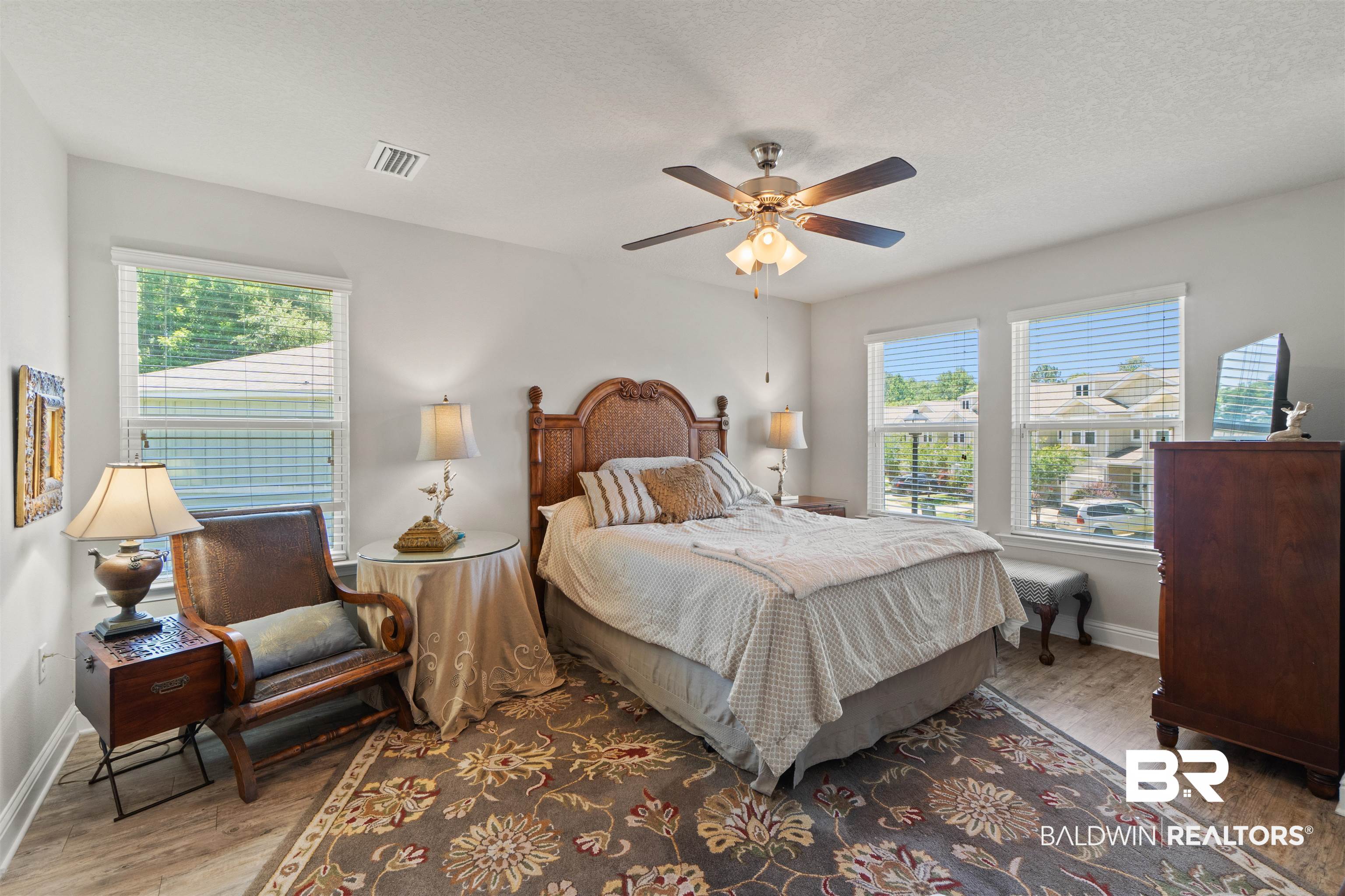 25806 Pollard Road, Unit 6 Daphne, AL 36526 - Photo 22 of 38 Spacious room featuring multiple windows with blinds, wood-finish flooring, and a ceiling fan with integrated lighting