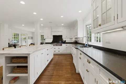 a large kitchen with stainless steel appliances a large counter top a stove a sink a refrigerator and a sink