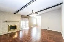 an empty room with wooden floor fireplace and windows