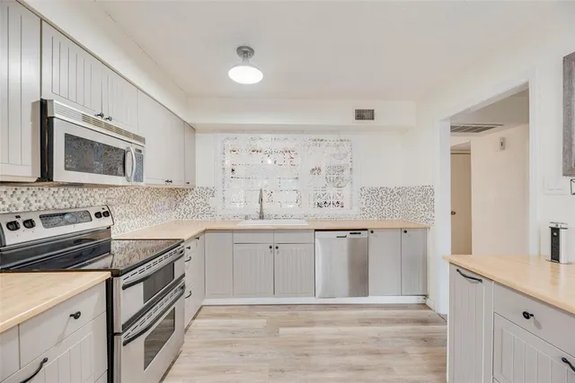 a kitchen with stainless steel appliances granite countertop a sink and dishwasher a stove top oven with wooden floor