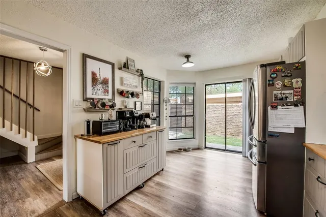 a kitchen with granite countertop a refrigerator a sink a stove and wooden floors