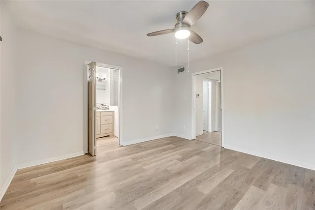 an empty room with wooden floor and ceiling fan