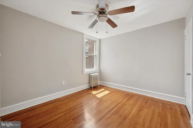 an empty room with a window and ceiling fan