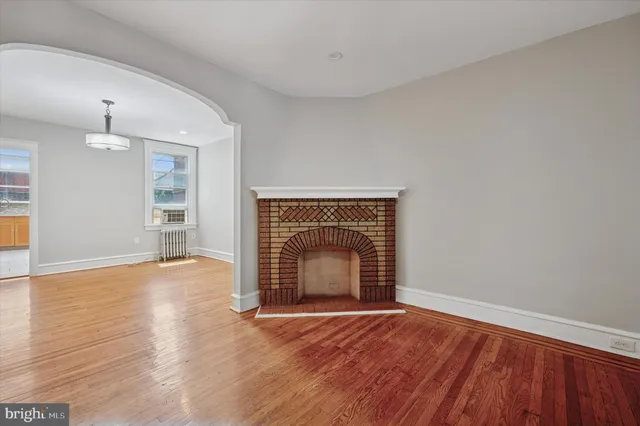 an empty room with wooden floor fireplace and window