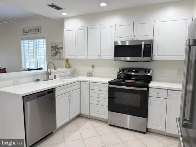 a kitchen with stainless steel appliances granite countertop a sink dishwasher a stove and a refrigerator with wooden cabinets