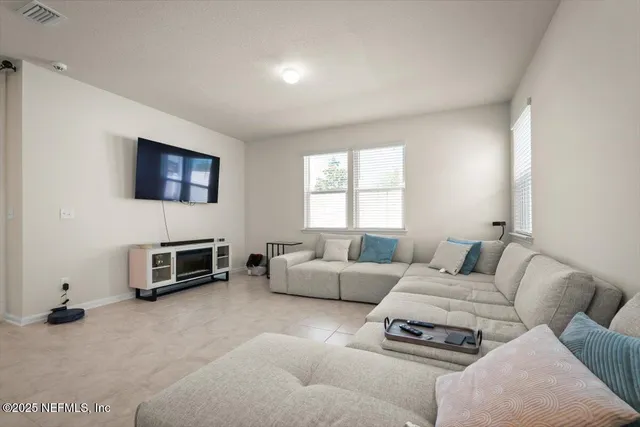 a living room with furniture a flat screen tv and a window