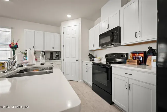 a kitchen with stainless steel appliances white cabinets a sink and a stove