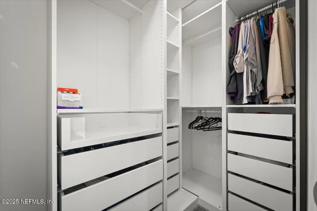 a view of walk in closet with clothes and shoes