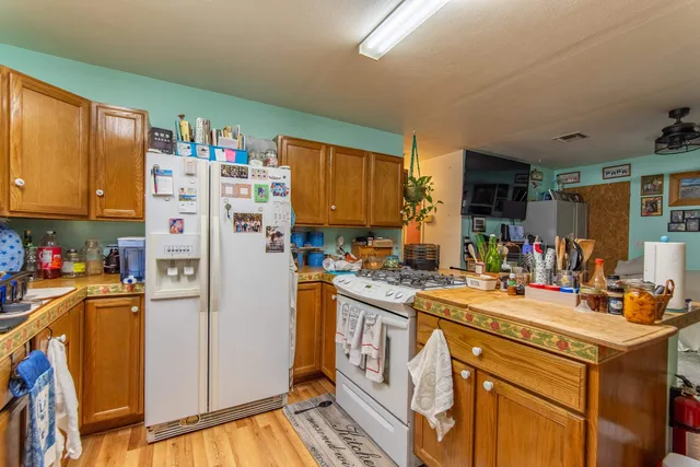 a kitchen with a refrigerator a stove a sink dishwasher and wooden cabinets with wooden floor