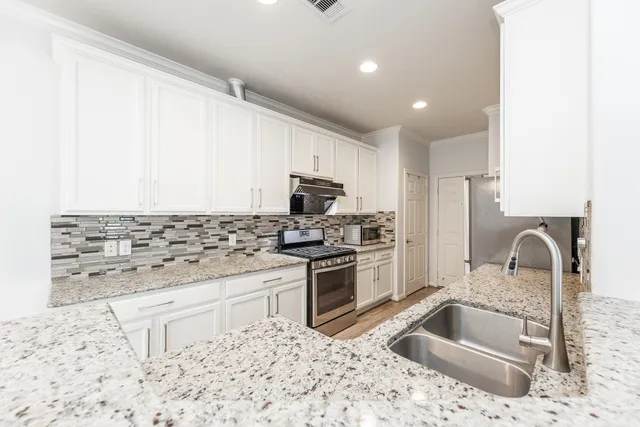 a kitchen with granite countertop a sink stainless steel appliances and cabinets