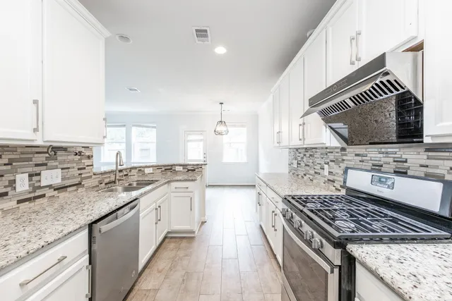 a kitchen with stainless steel appliances kitchen island granite countertop a sink stove and cabinets