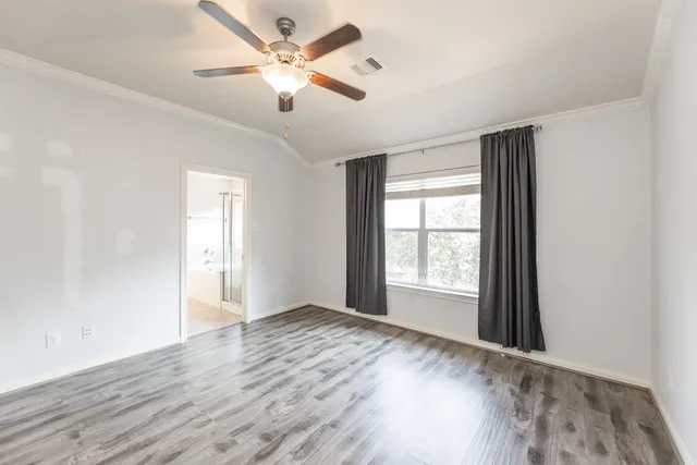 an empty room with wooden floor ceiling fan and windows