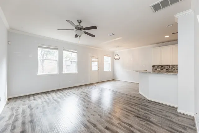 a view of an empty room with a window and wooden floor