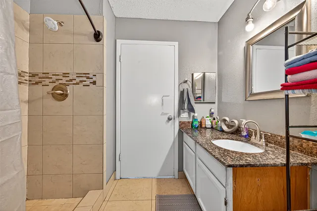 a bathroom with a granite countertop sink a mirror and shower