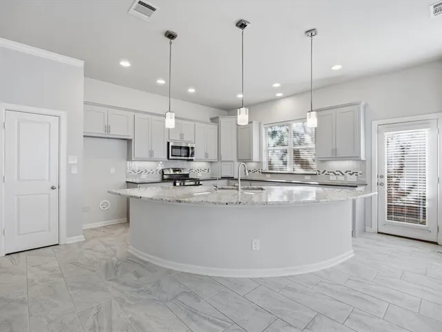 a large kitchen with kitchen island a sink a center island stainless steel appliances and a cabinets