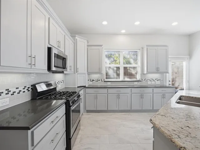 a kitchen with granite countertop a stove sink and cabinets
