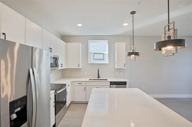 a kitchen with kitchen island a refrigerator a sink a stove a microwave and wooden floor