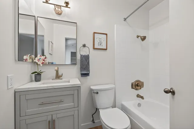 a bathroom with a toilet sink a mirror a vanity and shower