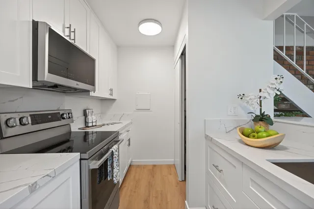 a kitchen with a sink and a stove top oven with wooden floor