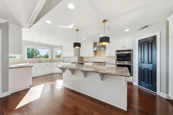 a kitchen with granite countertop a stove and white cabinets