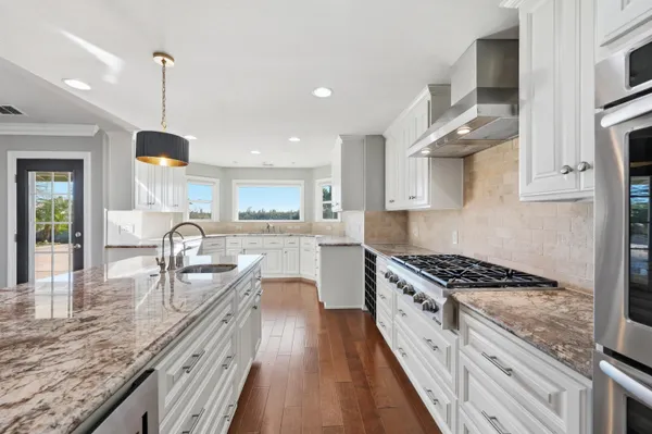 a kitchen with granite countertop white cabinets and white appliances with wooden floor