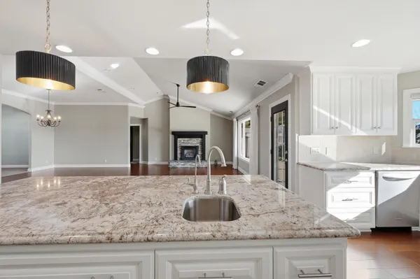 a kitchen with granite countertop white cabinets white appliances wooden floor and a window