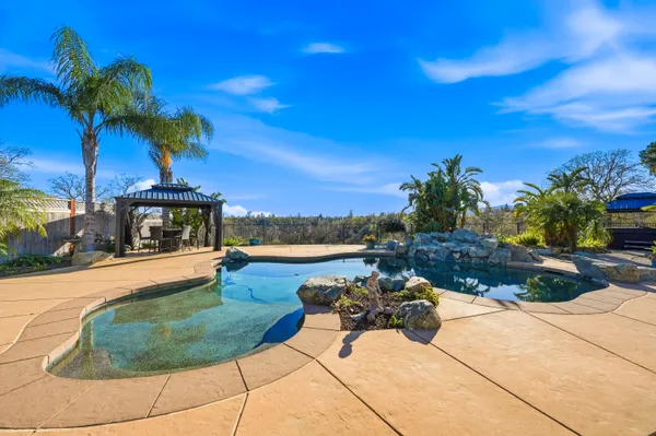a view of a swimming pool with a patio and a yard