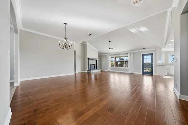 a view of a livingroom with wooden floor staircase and a kitchen
